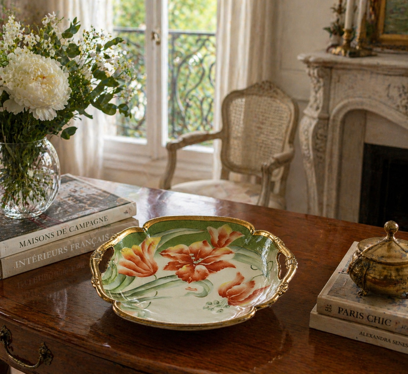 Decorative plate with floral design on a wooden table with books and flowers.