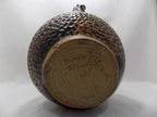 Ceramic jar with textured surface and visible signature on a white background