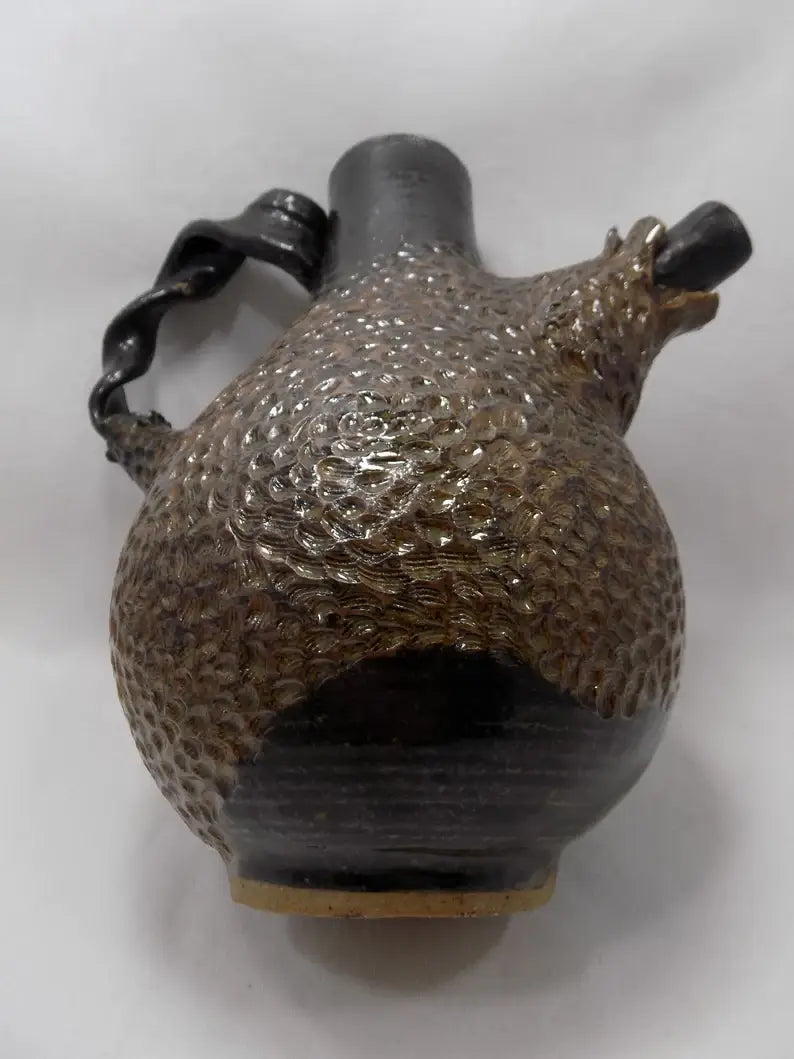 Decorative ceramic object with textured surface and black handles on a white background