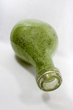 Green glass bottle on a white background tipped on side