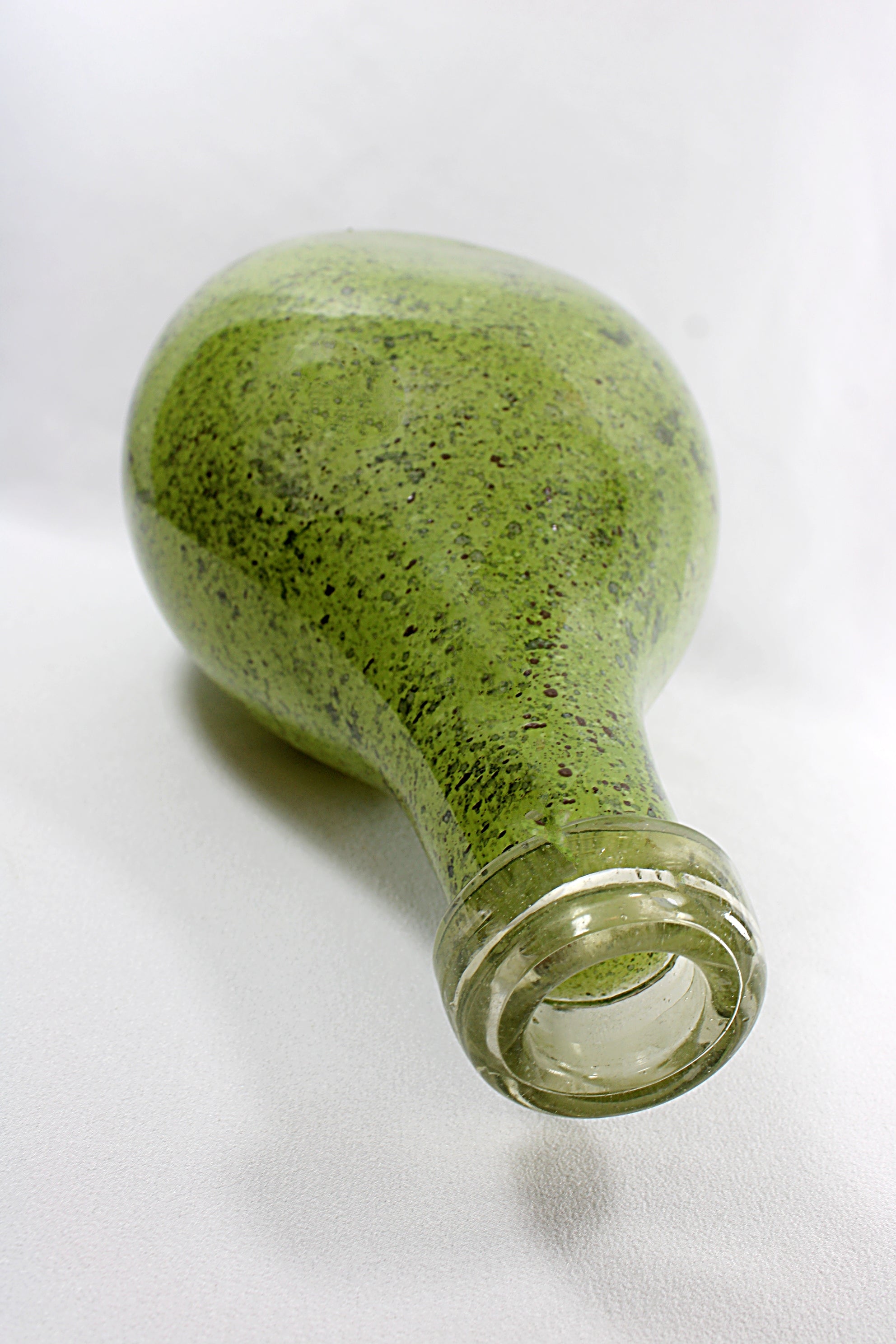 Green glass bottle on a white background tipped on side