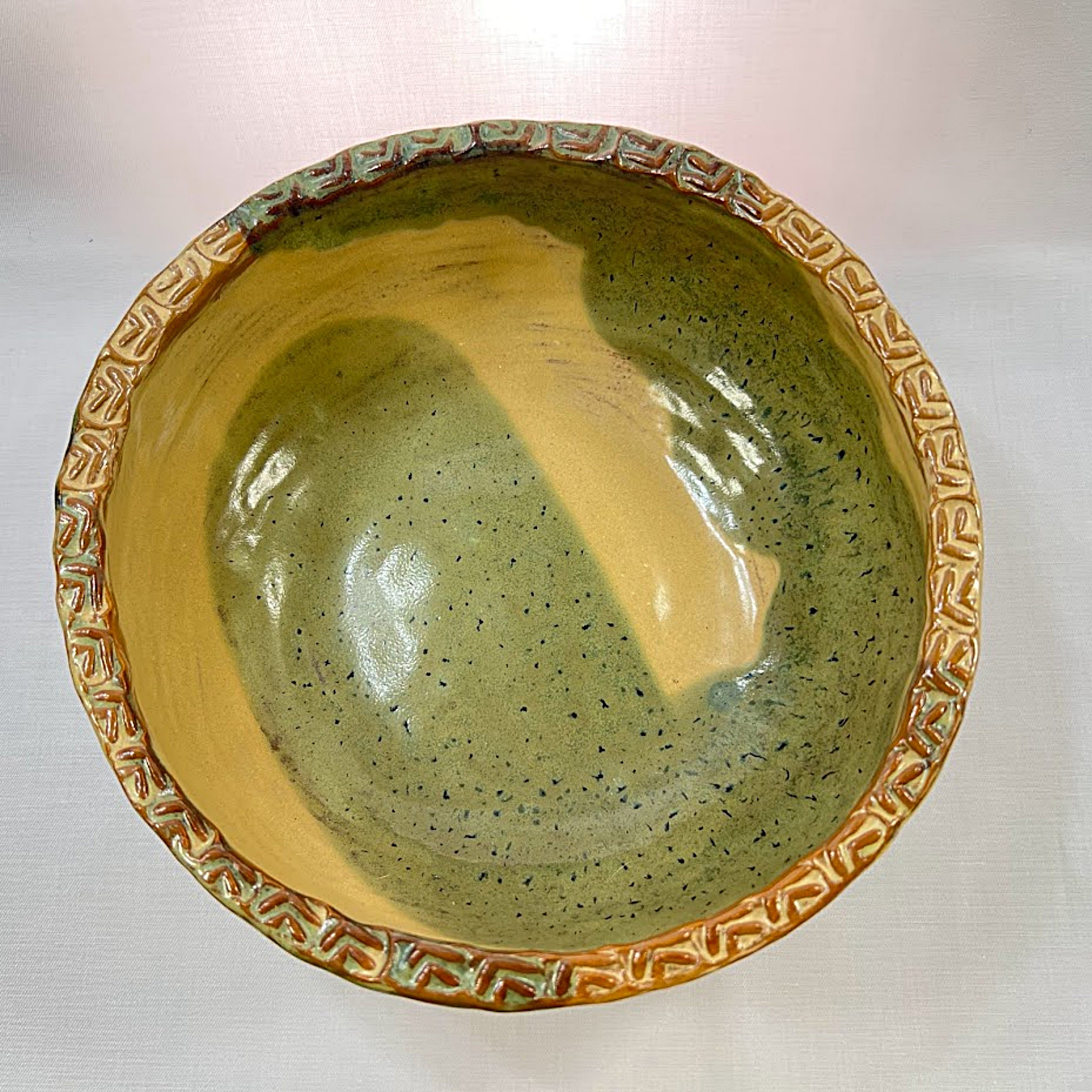 Ceramic bowl with green and beige interior on a white background