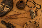 Collection of wooden artifacts including a mask, comb, and beads on a wooden surface.