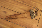 African Textile Tool Wooden Carved Fiber Comb with Forged Iron Spikes laying on wood table spikes up