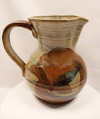 Ceramic pitcher with multicolored glaze on a white background by Bll Hyduck
