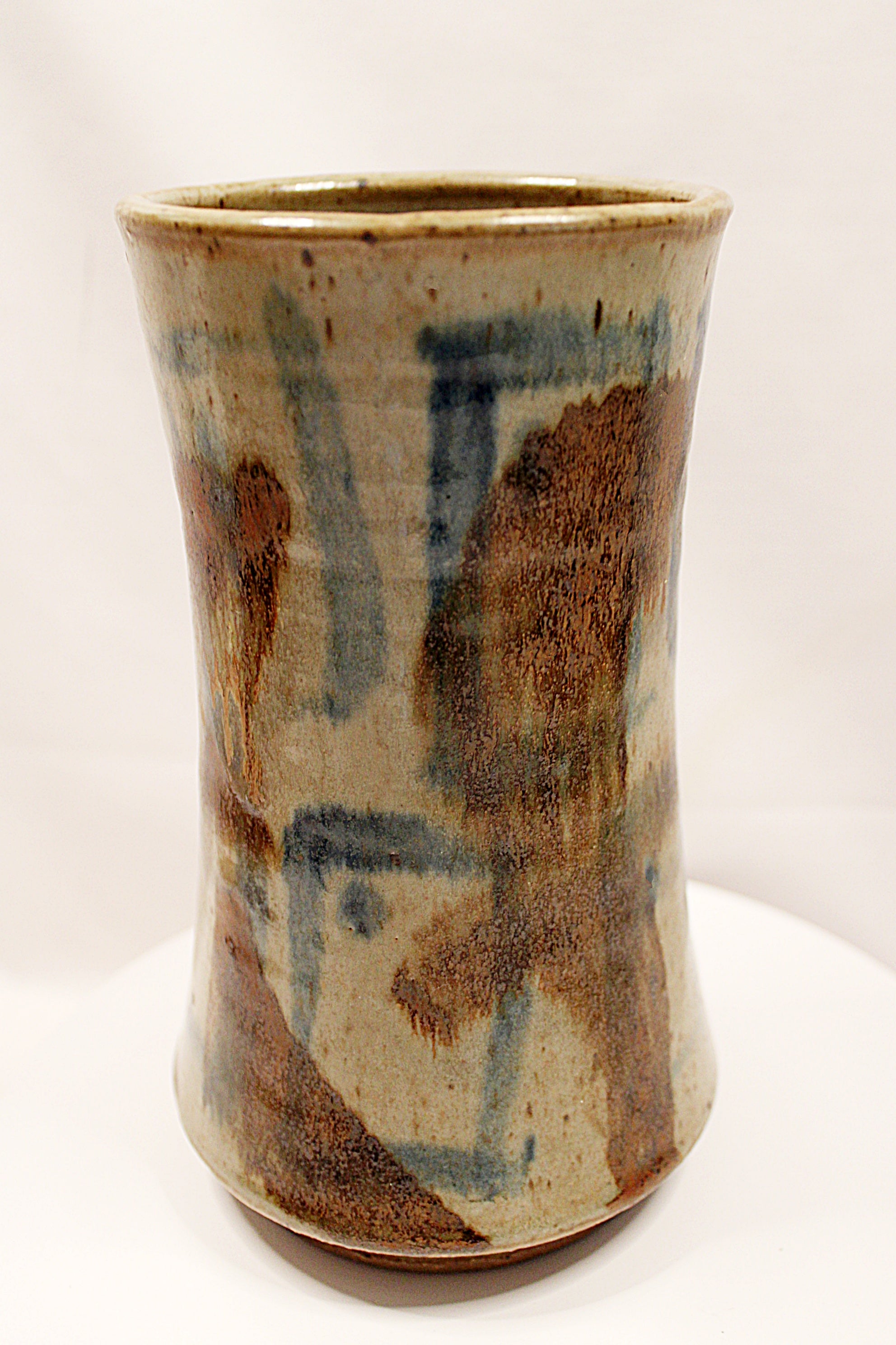 Cylindrical ceramic vase with abstract brown and blue patterns on a white background created by Bill Heduck potter -in 1993