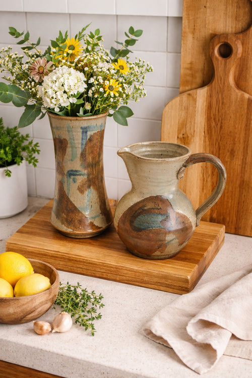 Ceramic pitcher and vase on a wooden cutting board with flowers and lemons. by Bll Heyduck 93
