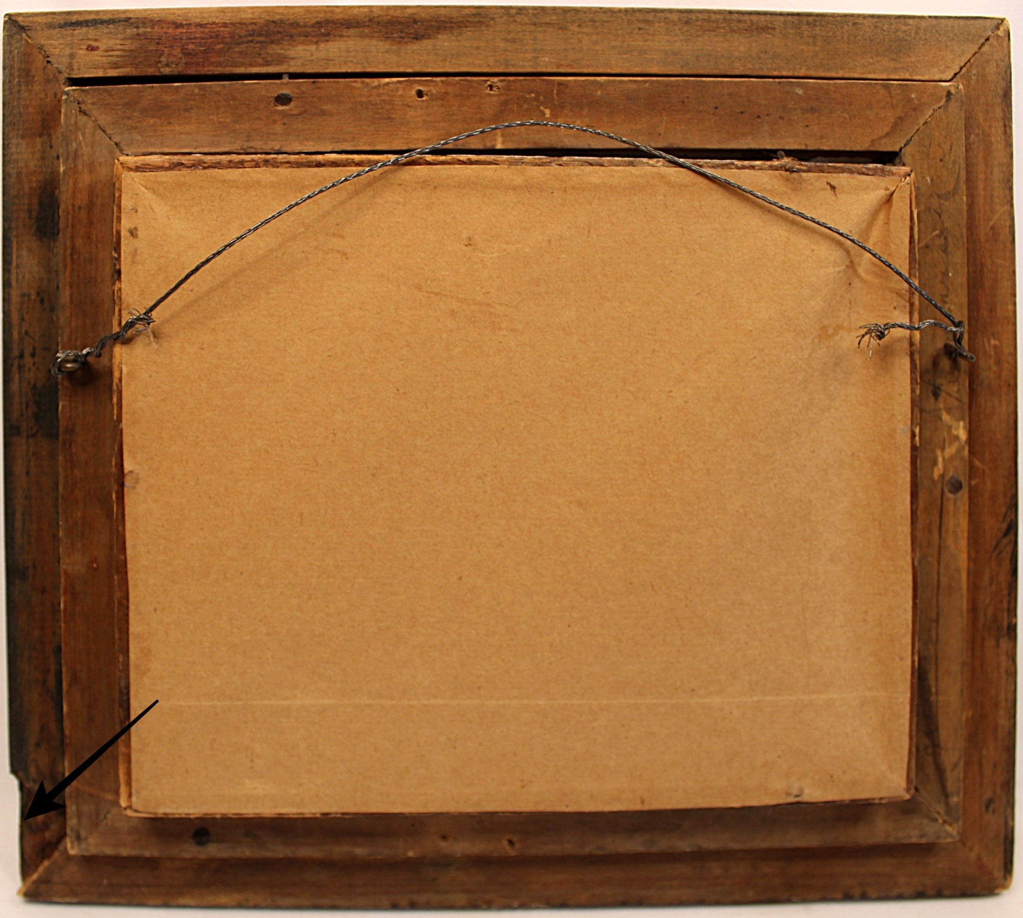 Back of a painting with a wooden frame and brown paper lining.