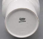 Close-up of a white ceramic product with 'Edelstein Bavaria' branding on a gray background