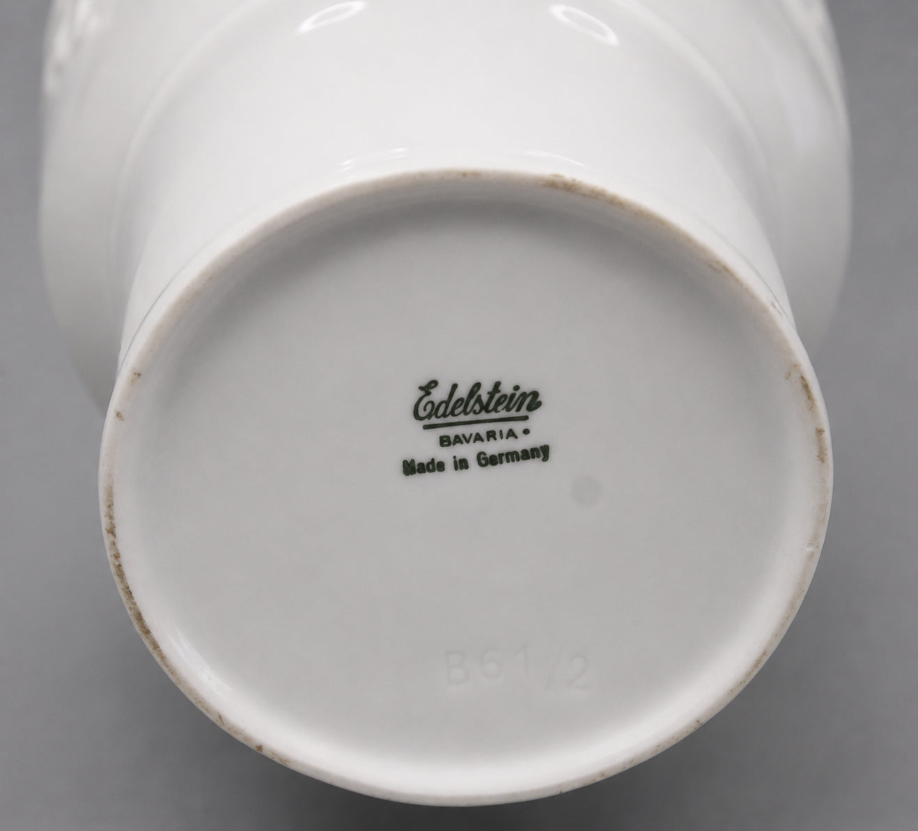 Close-up of a white ceramic product with 'Edelstein Bavaria' branding on a gray background