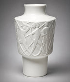 White ceramic vase with intricate carvings on a gray background