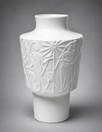 White ceramic vase with artistic embossed designs on a gray background