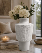 White decorative vase with floral arrangement on a table in a living room setting