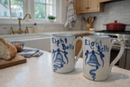 Two 'Eight Bells' mugs on a kitchen counter with a window and stove in the background.