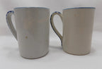 Two ceramic mugs with blue rims on a white background