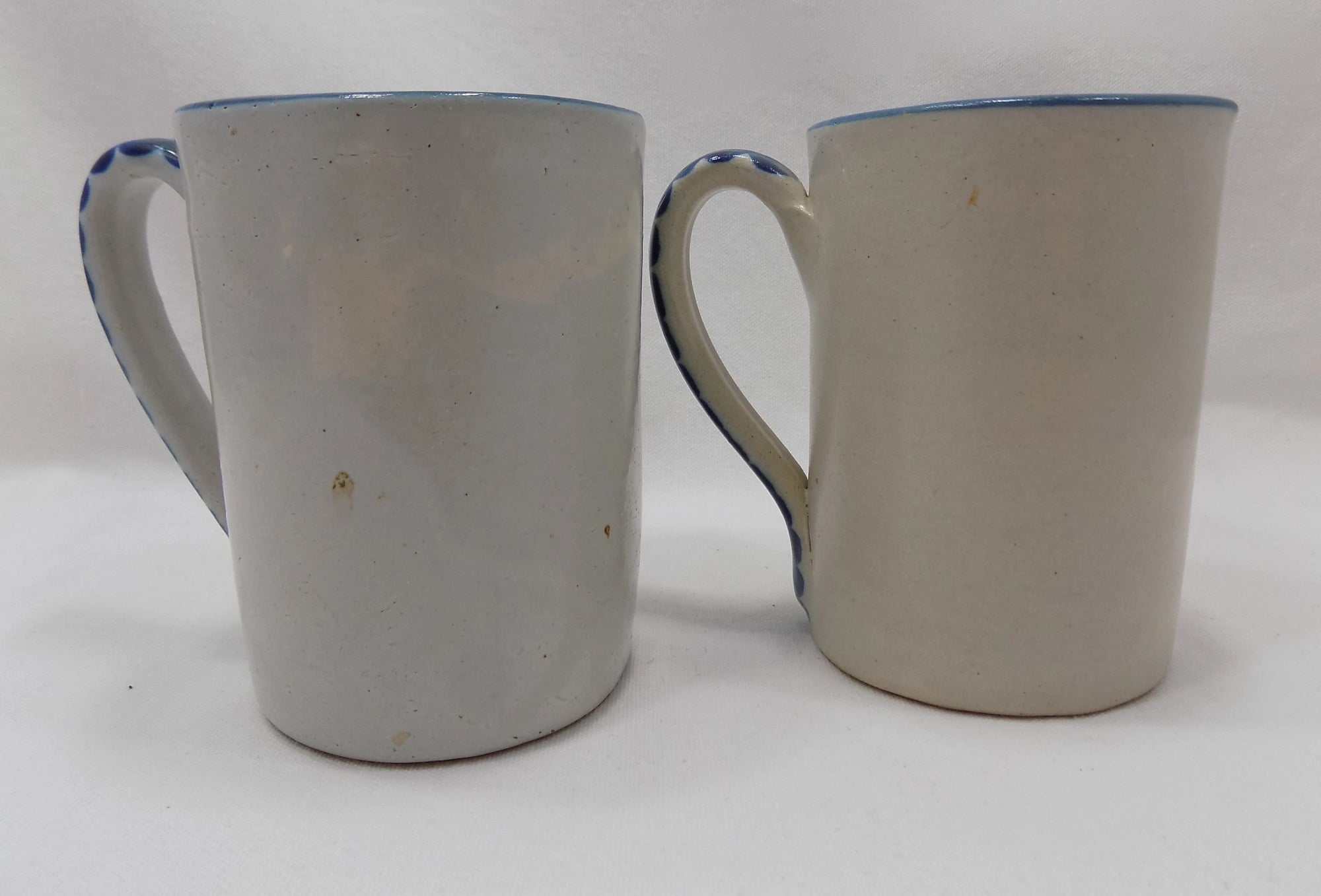 Two ceramic mugs with blue rims on a white background