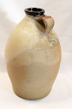 Beige ceramic vase with a single handle on a white background