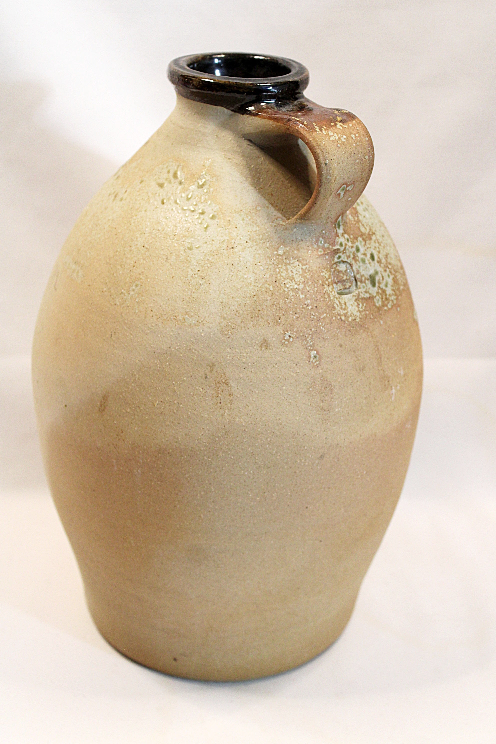 Beige ceramic vase with a single handle on a white background