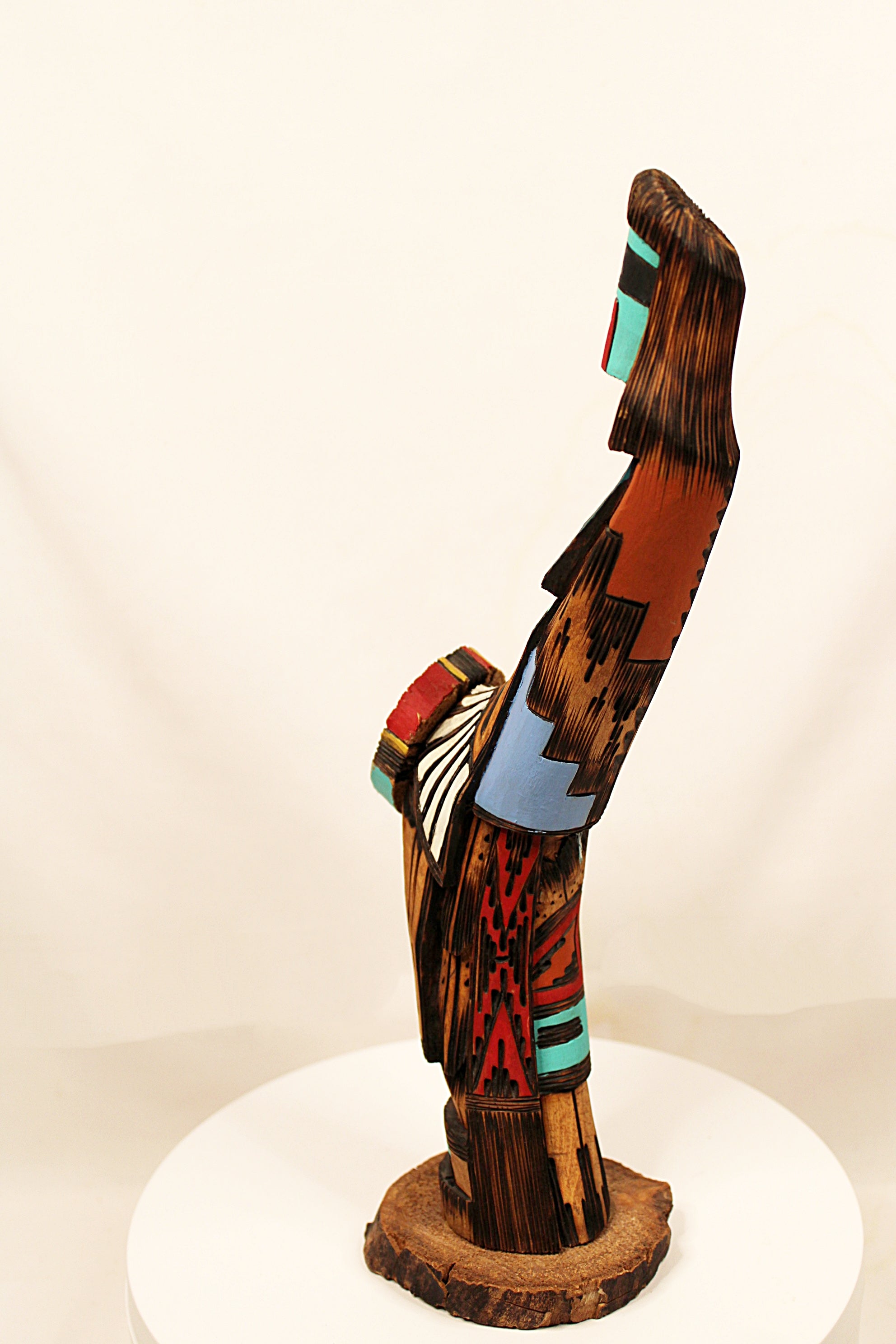 Colorful wooden sculpture on a white pedestal against a beige background