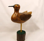 Wooden bird figure on a stand against a plain background signed seth 93