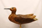Wooden bird decoy on a stand against a plain background Facing left
